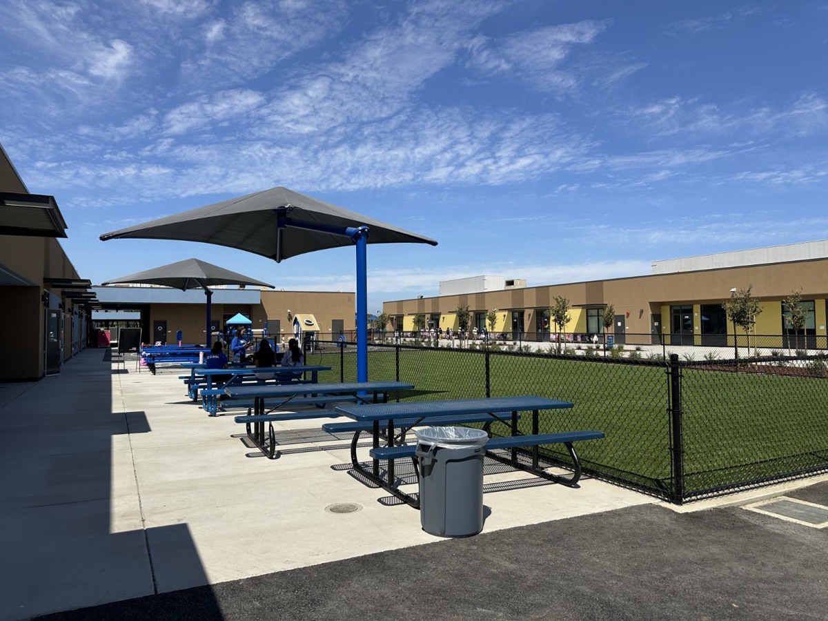Outdoor gathering area with shaded tables and lawn at Laurelwood Elementary School